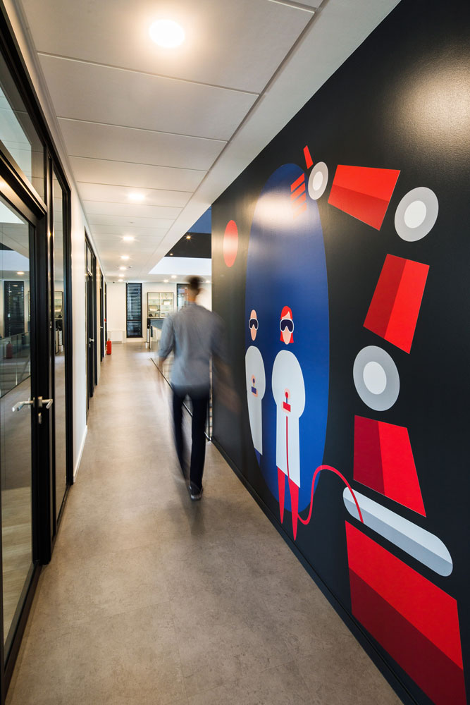 Person waling in the hallway next to Mono wall brand visuals